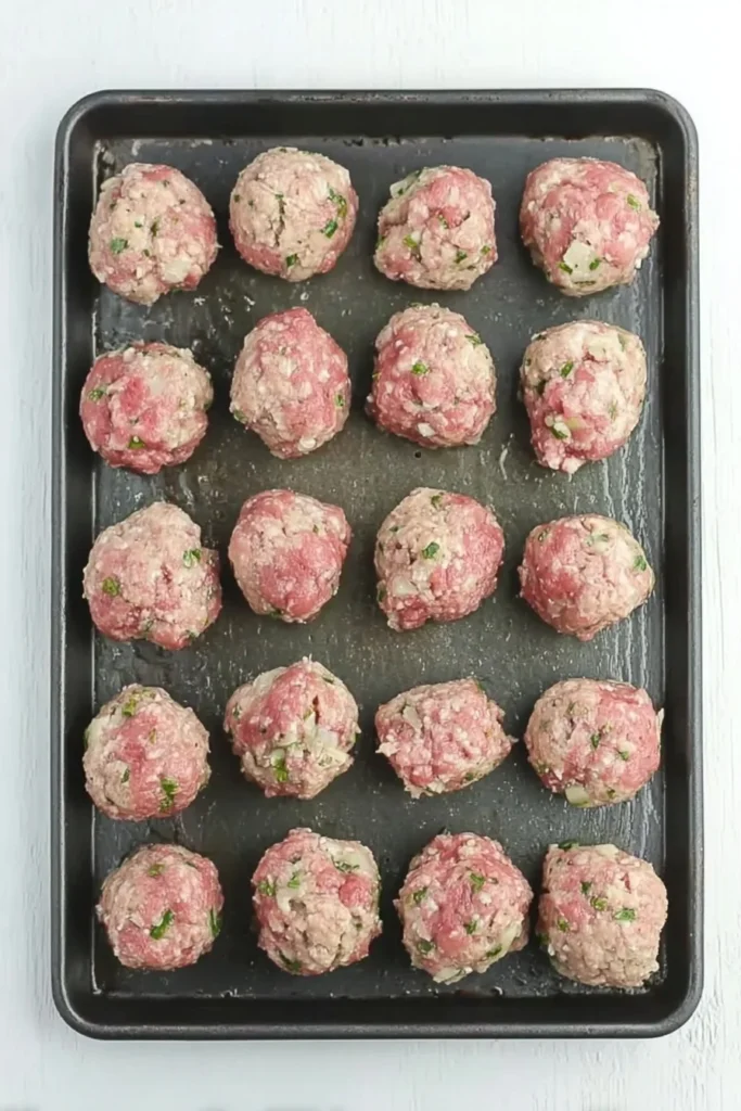 Raw Italian meatballs arranged on a baking tray before cooking